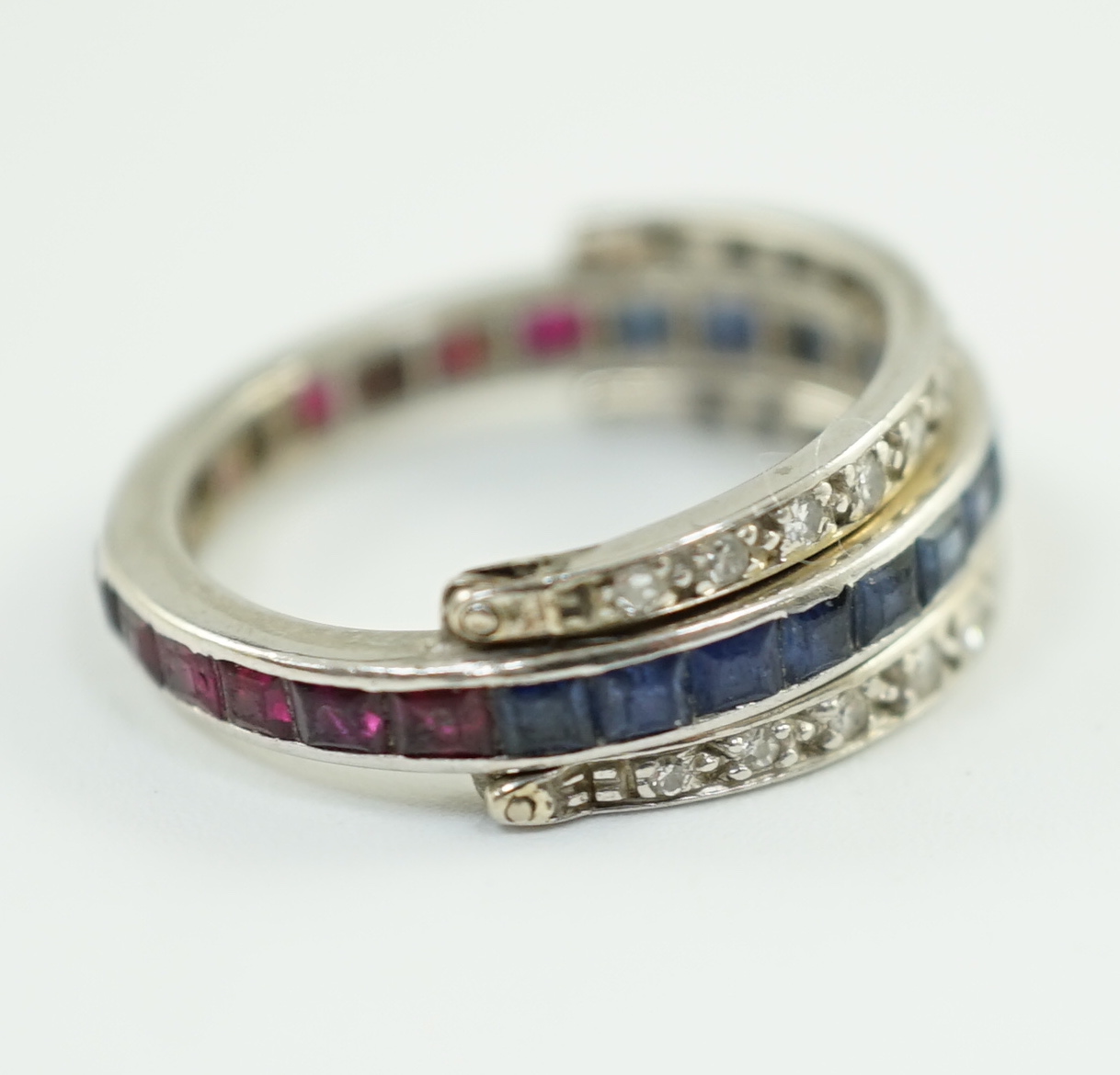 A mid 20th century white gold, diamond, ruby and sapphire set swivelling triple band eternity ring